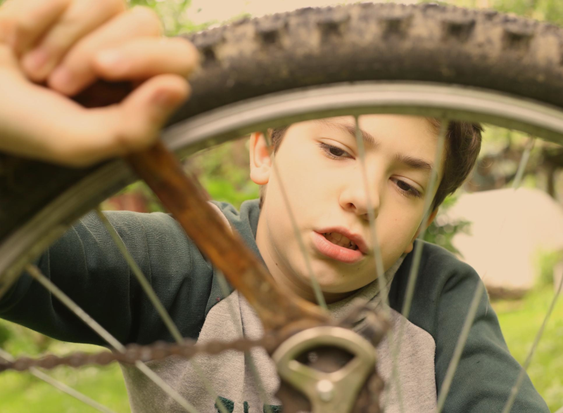 Junge schraubt mit Schraubschlüssel an einem Fahrrad