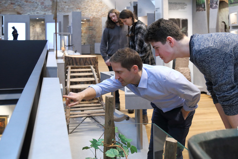 Personen beugen sich über Exponate