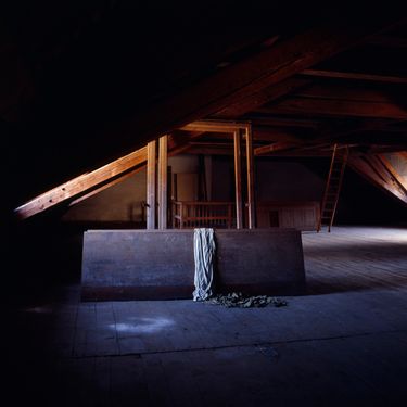 Das Foto zeigt einen dunklen Raum mit Lichteinfall, im Raum steht ein Tisch mit Tuch dar&uuml;ber