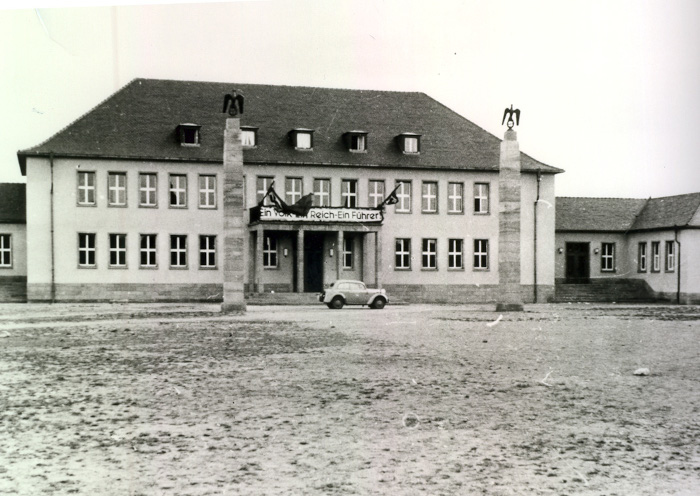 Front des Hauptgebäudes der heutigen Obermayr Europa-Schule in Rüsselsheim, von 1939 - 1945 in der Funktion als Parteiheim der Rüsselsheimer NSDAP; an dem "Führerbalkon" hängt ein Banner: "Ein Volk - Ein Reich - Ein Führer!", links und Rechts davon zwei Säulen mit Reichsadler-Figuren