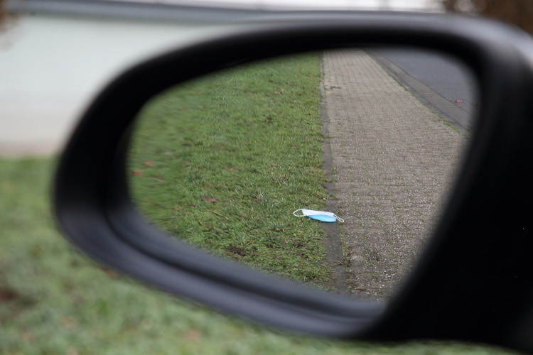Autorückspiegel, in dem eine auf dem Boden liegende Maske zu sehen ist